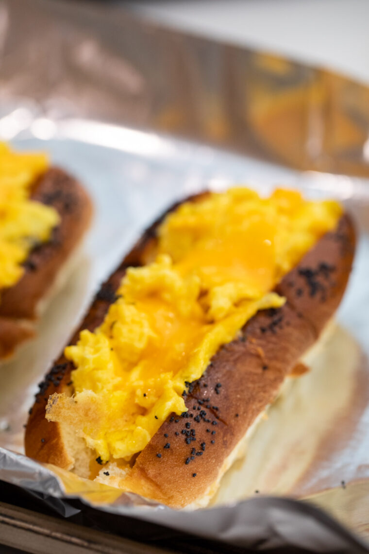 Piling eggs on breakfast dogs.