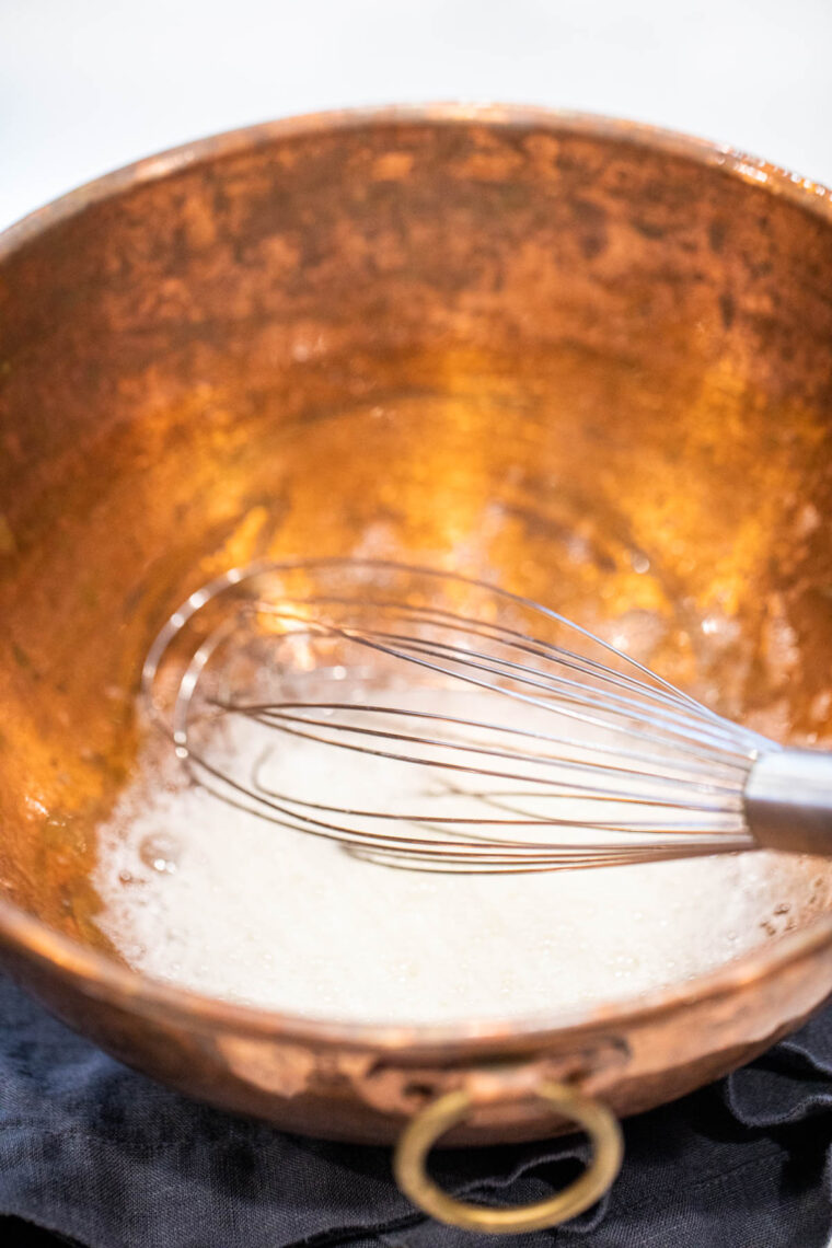 Whisking egg whites in a copper bowl.